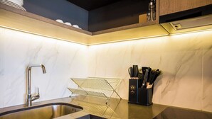 A modern kitchen with a stainless steel sink, a black countertop, and a knife block. - Prime 2BR Oasis in the Heart of Las Condes (Unknown)