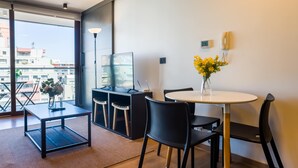 Een moderne kamer met een eettafel, stoelen, een televisie en een vaas met bloemen.