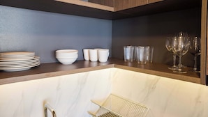Een keuken met marmeren aanrechtbladen, houten kasten en een metalen rek.