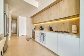 A modern kitchen with a wooden backsplash, stainless steel appliances, and a built-in oven. - Modern Corner Condo with Epic Pool at SOHO (Puerto Vallarta)