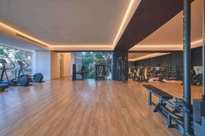 Ein geräumiger Fitnessraum mit Laufbändern, Krafttrainingsgeräten und einer Sitzbank.