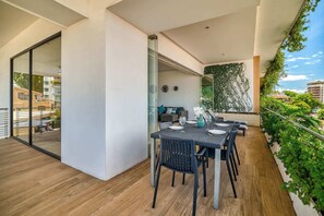 Ein moderner Balkon mit Esstisch für vier Personen, umgeben von Pflanzen und Blick auf die Stadt.