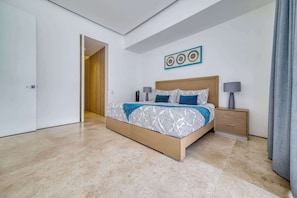 A modern bedroom with a large bed, bedside tables, and a wooden door.