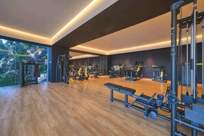 A modern gym with various exercise equipment, large windows, and a wooden floor. - Modern Corner Condo with Epic Pool at SOHO (Puerto Vallarta)