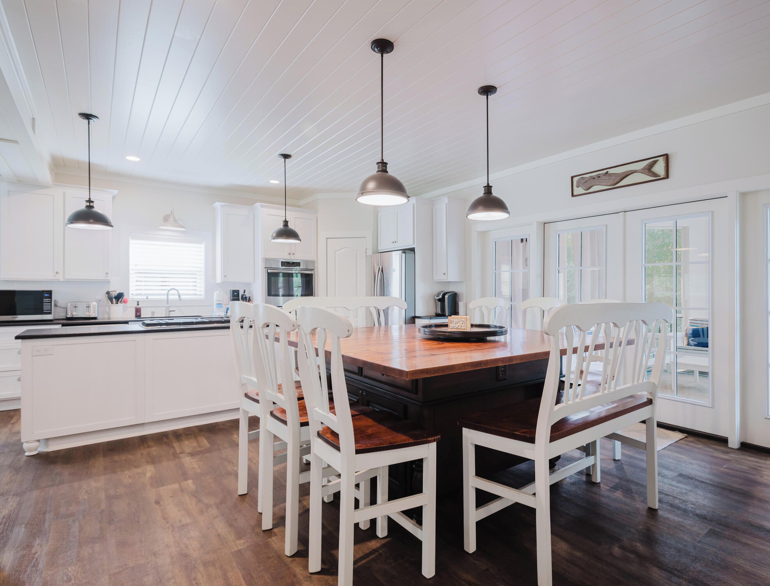Een moderne keuken met witte kasten, een houten eiland en hanglampen.