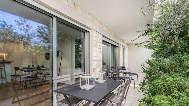 An outdoor dining area with a large table and chairs, surrounded by glass doors and windows. - Olea Suite Pomegranate (Polignano a Mare)