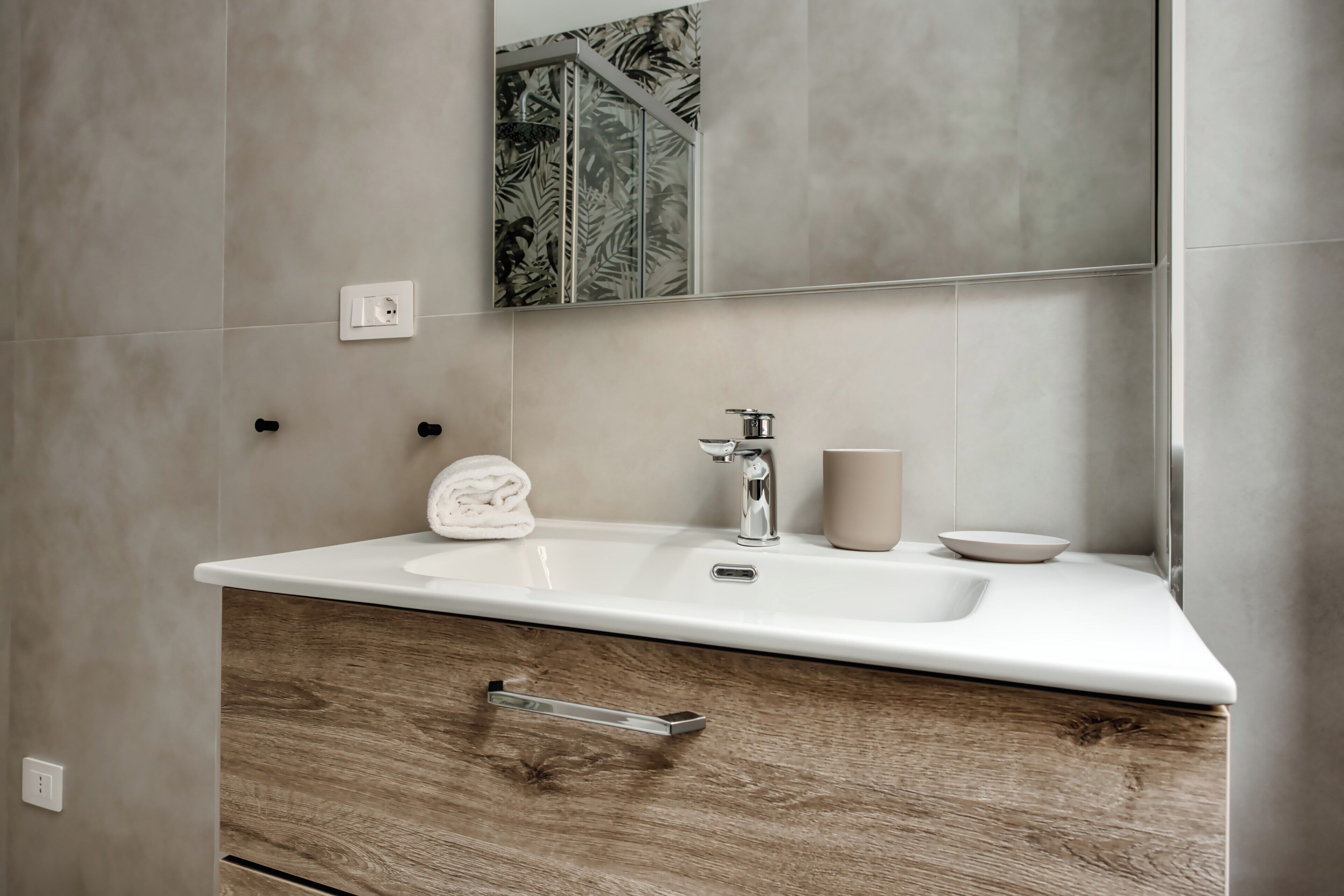 Une salle de bain avec un lavabo blanc, un miroir et un meuble en bois.