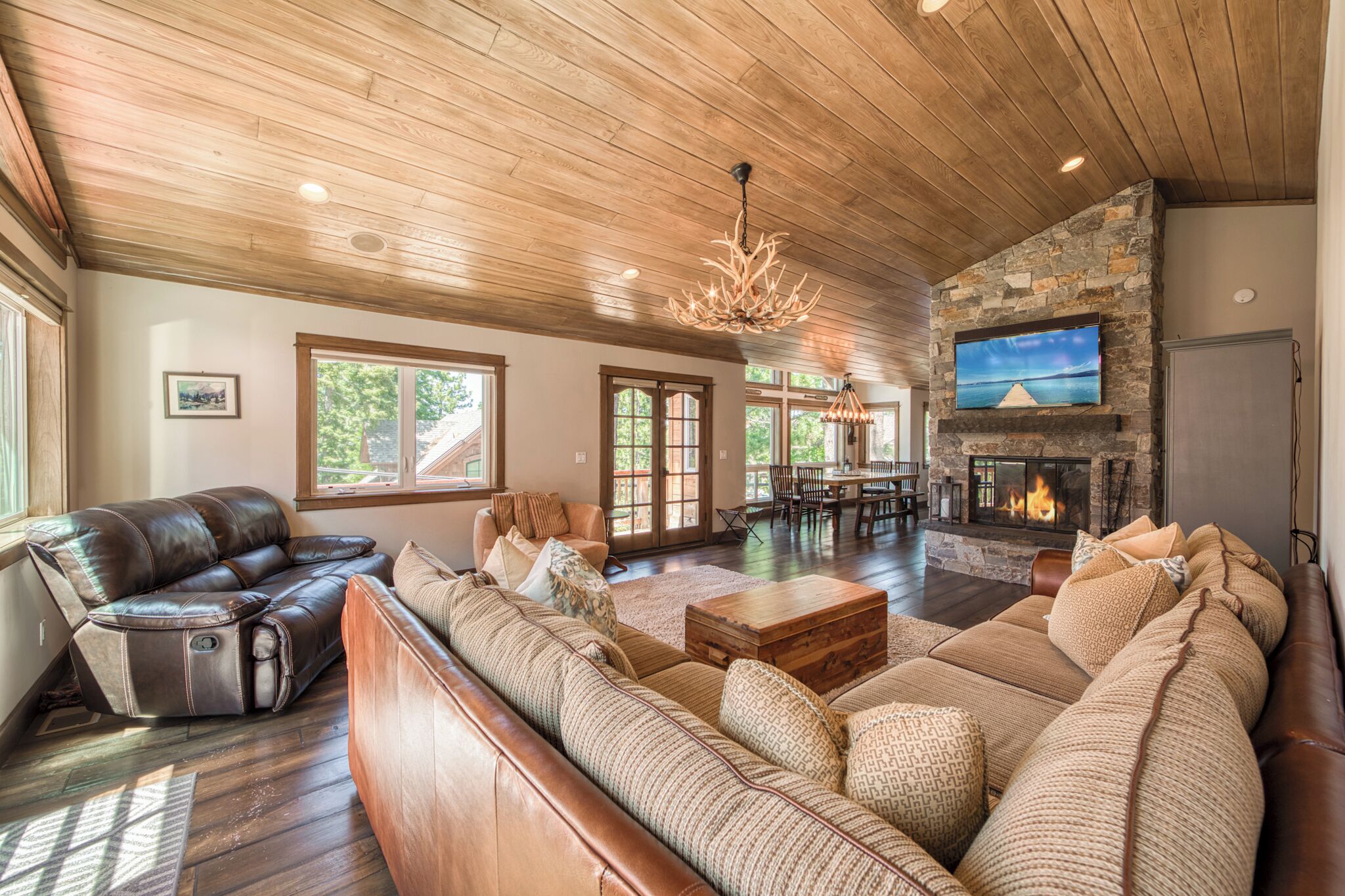 A spacious living room with a stone fireplace, leather sofas, and a dining area.
