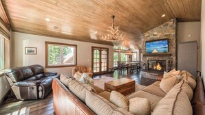 A spacious living room with a stone fireplace, leather sofas, and a dining area.