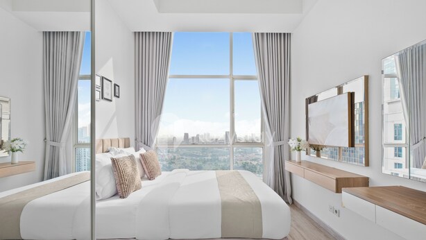 Ein modernes Hotelzimmer mit einem großen Bett, Blick auf die Stadt und einem großen Spiegel.