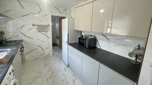 A modern kitchen with white marble tiles, a built-in oven, a microwave, and a sink. - Construction Crew Quarters:5brfree Wifi & Parking (Newcastle-upon-Tyne)