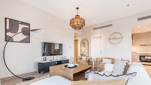 A modern living room with a wooden coffee table, white sofas, and a chandelier.
