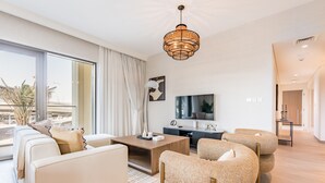 A modern living room with a sofa, armchairs, a coffee table, and a TV.
