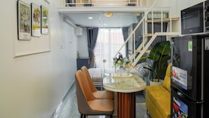 A modern interior with a dining area, a sofa, a refrigerator, and a staircase. - Lilo's Homestay (Hanoi)
