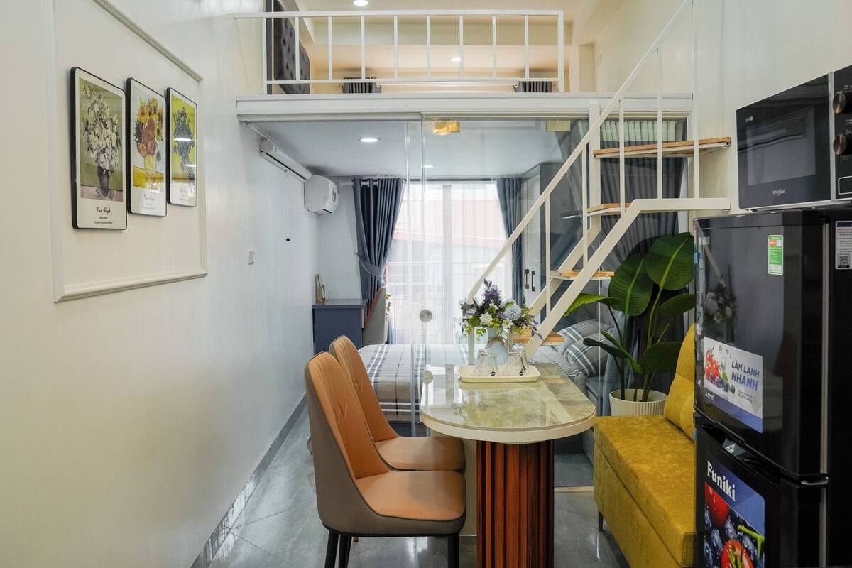 Un intérieur moderne comprenant un coin repas, un canapé, un réfrigérateur et un escalier.