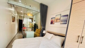 A hotel room with a large bed, a wardrobe, a glass partition, and a view of the outside. - Lilo's Homestay (Hanoi)