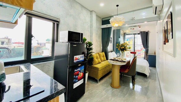 A compact hotel room with a kitchenette, a sofa, a dining table, and a bed. - Lilo's Homestay (Hanoi)