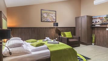 Een hotelkamer met een bed, een bureau, een stoel, een kast en een televisie.