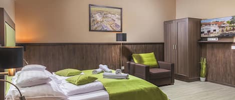 A hotel room with a bed, a desk, a chair, a cabinet, and a television.