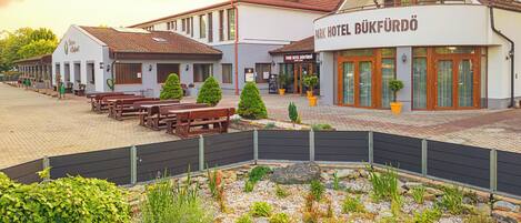 Ein Hotel mit Außenbereich, einem kleinen Teich und einem gepflegten Garten.