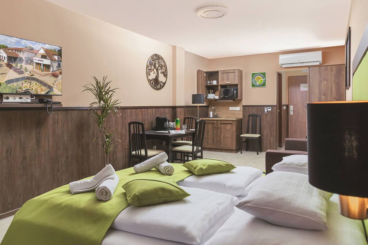 Une chambre d’hôtel avec deux lits, un petit coin cuisine, une table à manger et un comptoir de réception.