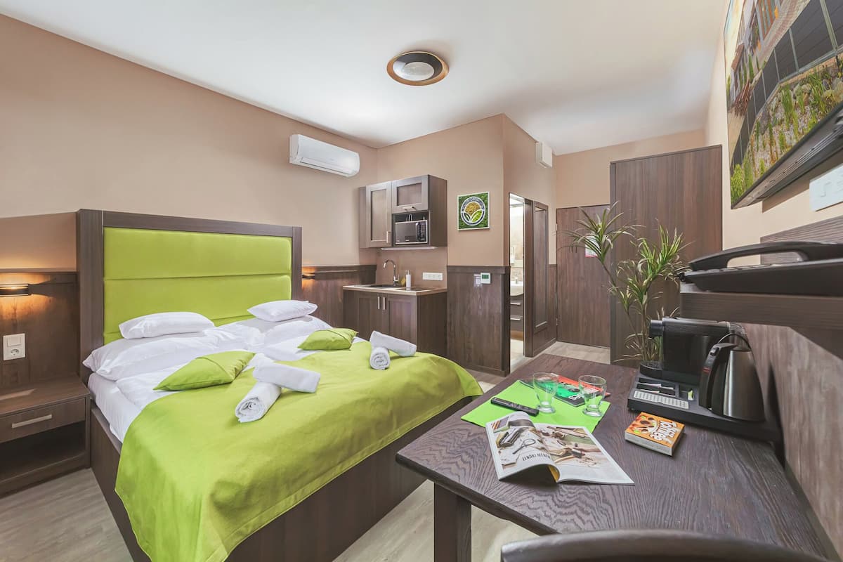 Une chambre d’hôtel équipée d’un lit, d’un bureau, d’un four à micro-ondes, d’un lavabo et d ’une plante.