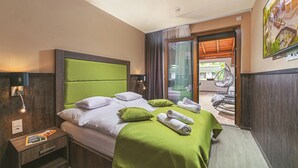 A hotel room with a bed, a nightstand, a window with curtains, a view of the outside, and a door leading to a balcony. - Park Hotel Bükfürdő (Bükfürdo)