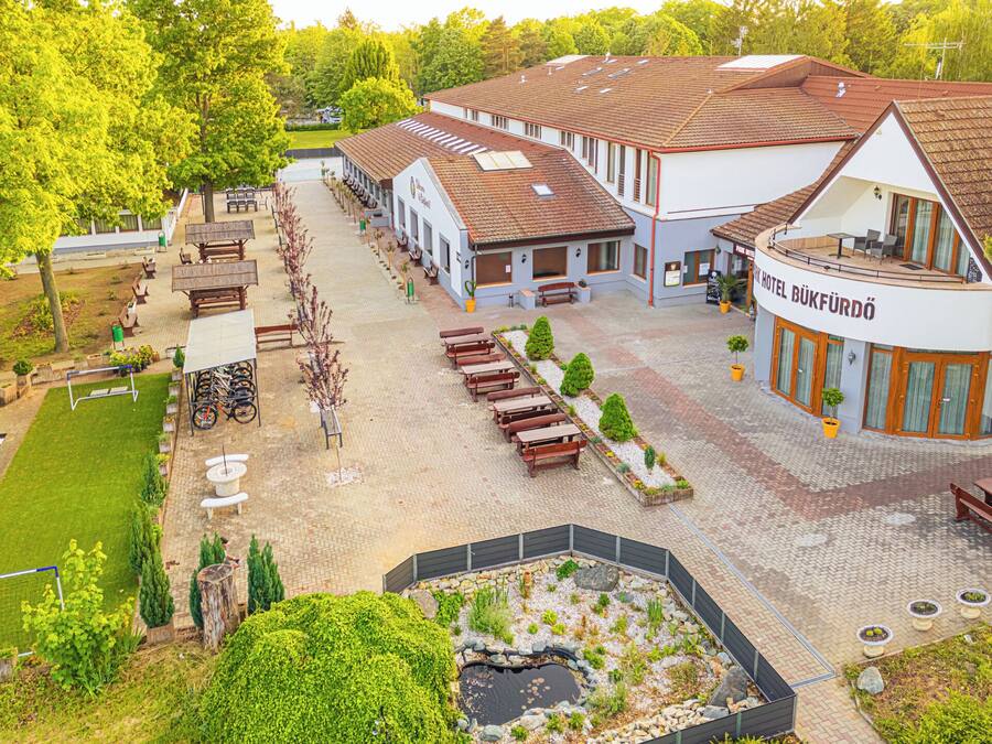 A hotel with a courtyard, outdoor seating, and a pond.