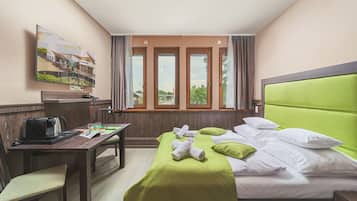 A hotel room with a bed, a desk, a chair, a coffee machine, and a painting on the wall.