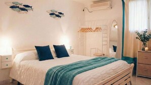 A bedroom with a bed, two bedside tables, a wardrobe, a mirror, and wall decorations. - Nice apartment for 7 people with A/C, WIFI and pets allowed (Baunei)