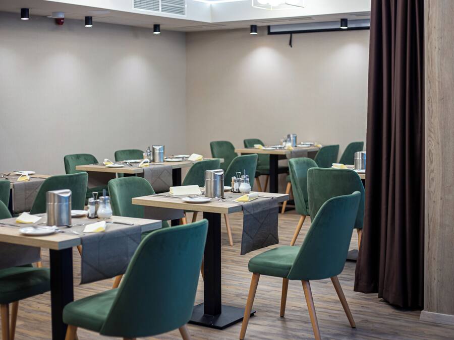 A conference room with multiple tables and chairs, equipped with water pitchers, cups, and notepads.