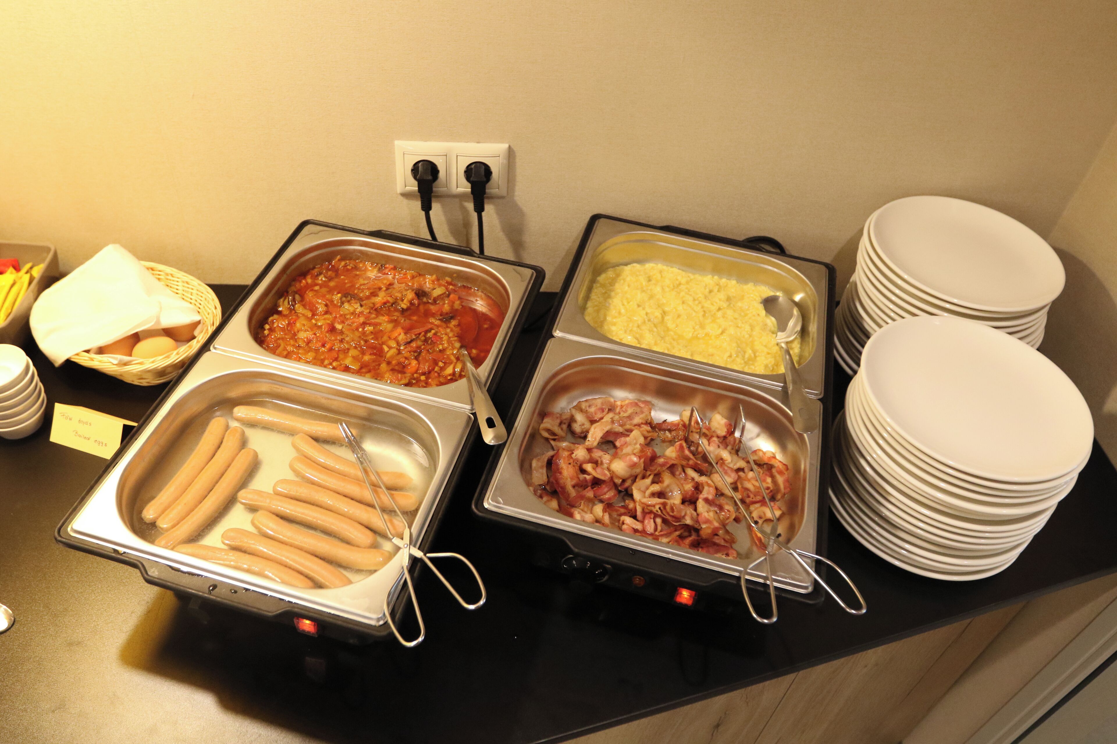 Een buffet met diverse gerechten, waaronder worst, pasta en rijst.