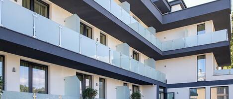 Un edificio moderno de varios pisos con balcones, ventanas amplias y techo plano.