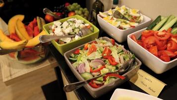 Un bufé con ensaladas y frutas variadas.