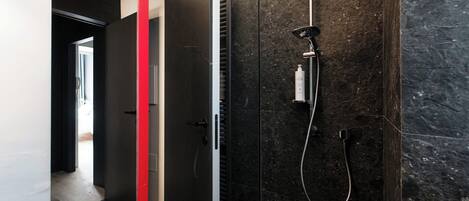 A modern bathroom with a shower, a glass enclosure, and a red accent wall.
