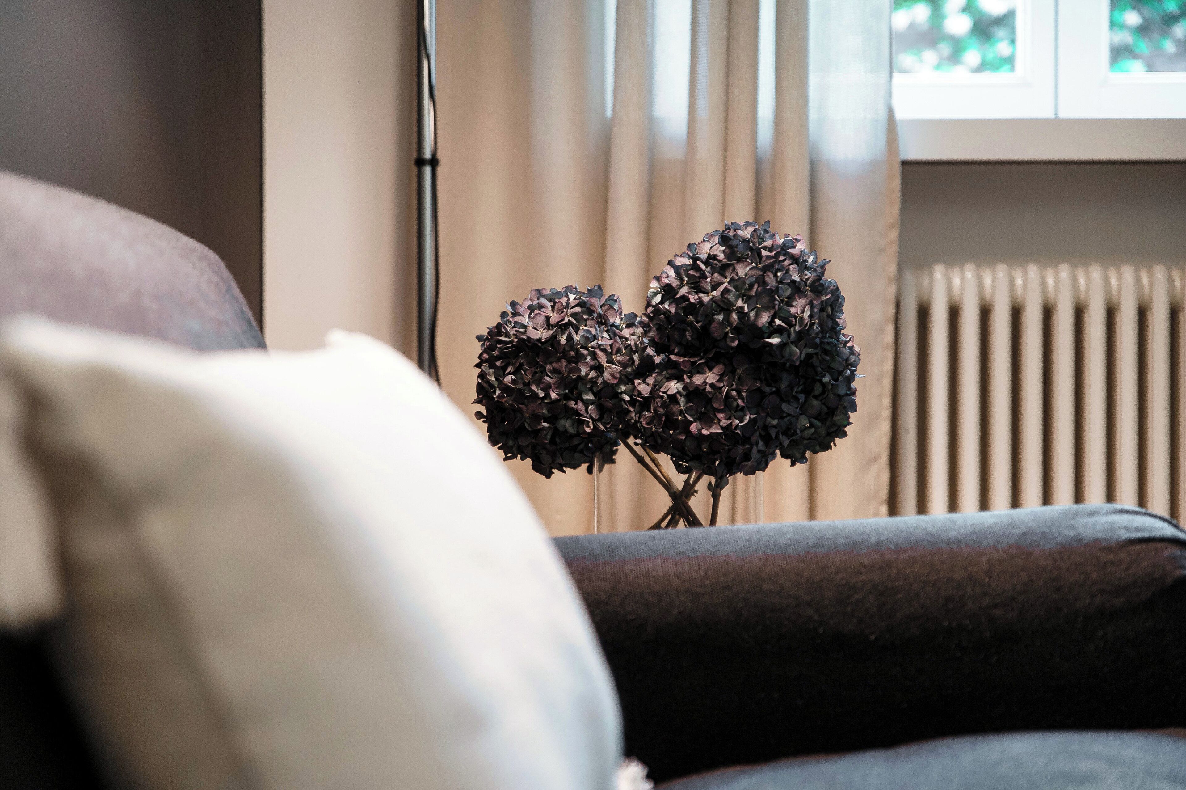 Ein Wohnzimmer mit einer Couch, einem Heizkörper und einem Fenster mit Vorhängen.