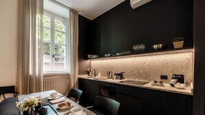 Una cocina moderna con un salpicadero oscuro, una encimera con varios utensilios de cocina y un comedor con una mesa dispuesta para dos.