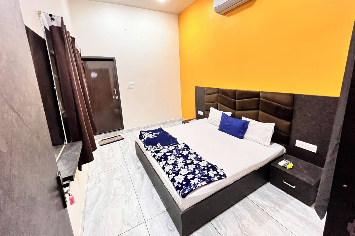 Une chambre d’hôtel équipée d’un lit, d’une table de chevet, d’un tiroir, d’une porte et d’un appareil de climatisation.