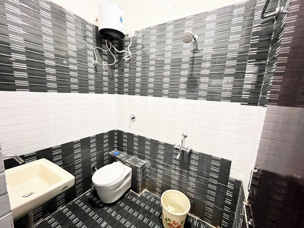 A bathroom with a toilet, sink, and shower. The walls have a black and white striped pattern. - Hotel Shree Bageshwar Inn (Ujjain)