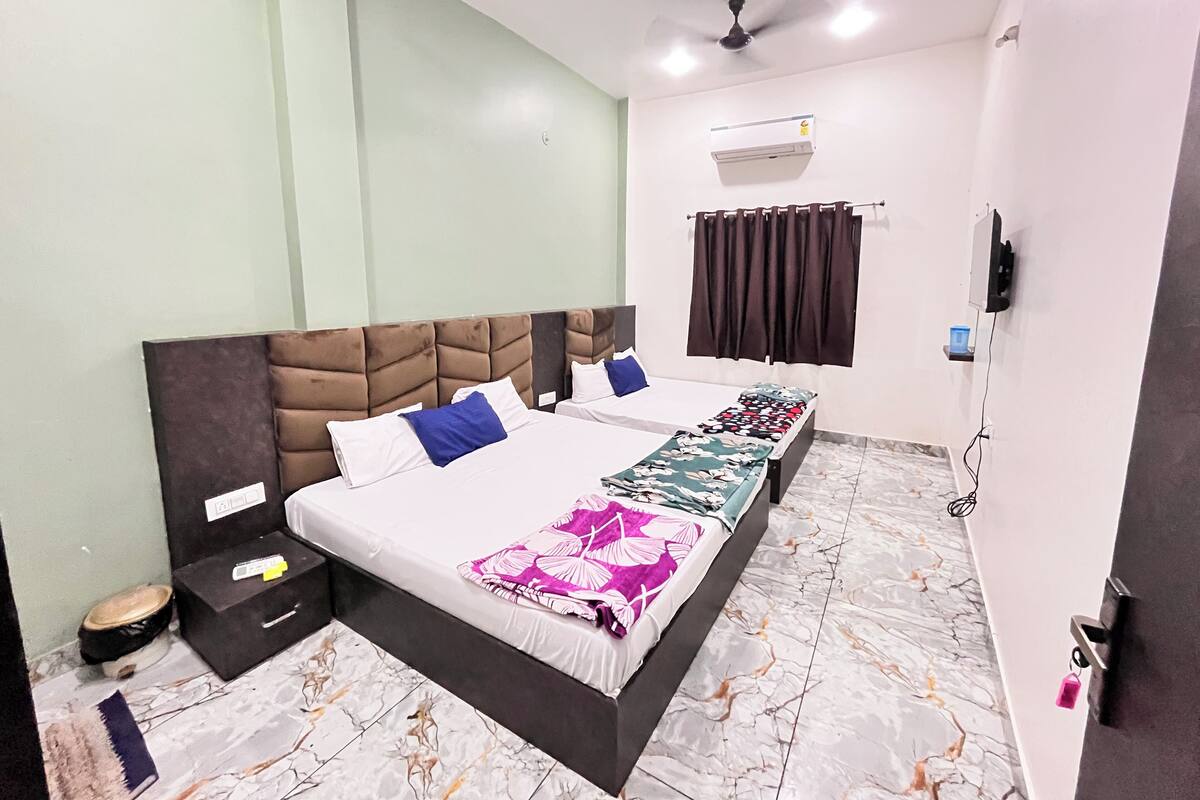 Une chambre d’hôtel avec un grand lit, un ventilateur de plafond, un appareil de climatisation et une fenêtre avec des rideaux.