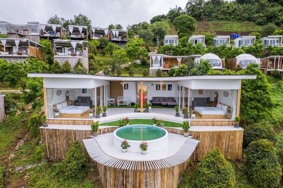 Una vila de luxe amb piscina privada, envoltada de vegetació exuberant i altres cases particulars.