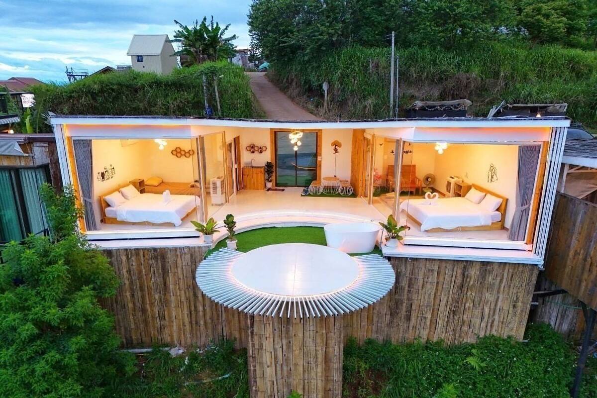 Un espai de vida modern i diàfan amb una zona de seients circular, dues habitacions i un espai central obert.