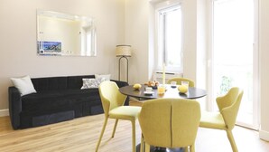 Un soggiorno moderno con un divano nero, poltrone gialle, un tavolo rotondo con accessori per la colazione, un grande specchio e una lampada da terra.