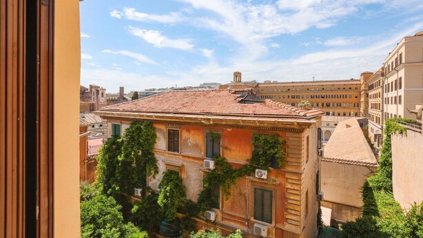 Un edificio con tetto in tegole, diverse finestre e condizionatori.