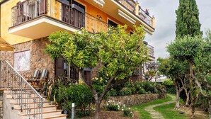 A residential building with a stone facade, a staircase leading to a balcony, and a garden with a lawn and a tree. - Nice apartment in villa for 5 people with A/C, WIFI, pool, terrace and pets allowed (Borghetto Santo Spirito)