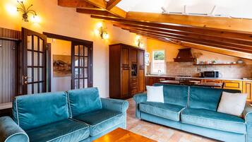 Un soggiorno accogliente con due divani blu, un tavolino in legno e una cucina sullo sfondo.