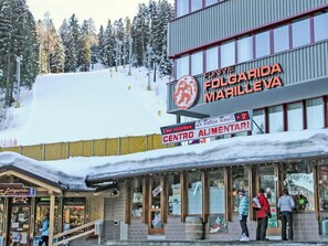 Un bâtiment avec une enseigne indiquant « Funivia Follarda Marilèva » et une autre indiquant « Centro Alimentari ».