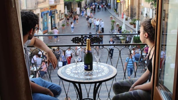 Un balcón con una mesa, una botella de champán y dos personas sentadas.