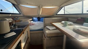 Eine kleine Kombüse mit Bett, Spüle und Tisch mit Geschirr.