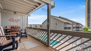 A balcony with wooden chairs and a view of a swimming pool. - Relax, Explore, and Make Memories at Shipwatch Pointe I 216 F (Myrtle Beach)